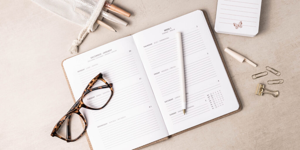 Flatlay stilleven van een agenda met schrijfwaren en een bril - Lifestyle fotografie