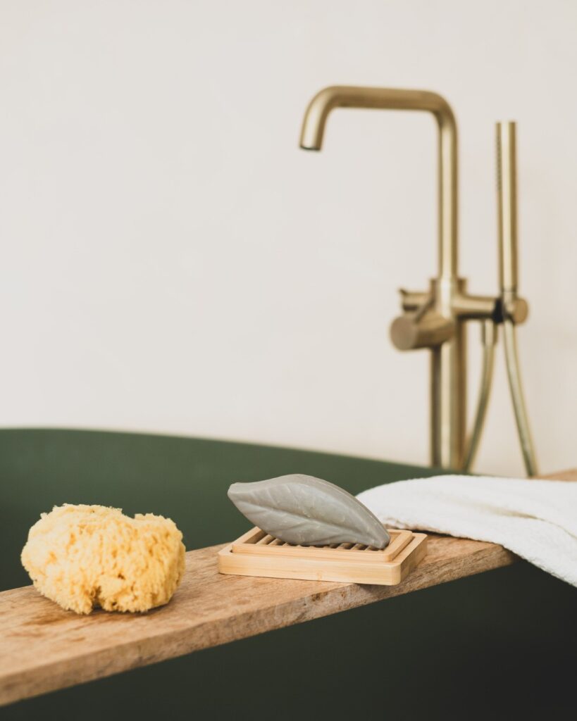 sfeervolle productfotografie van duurzame badproducten op houten plank met gouden kraan