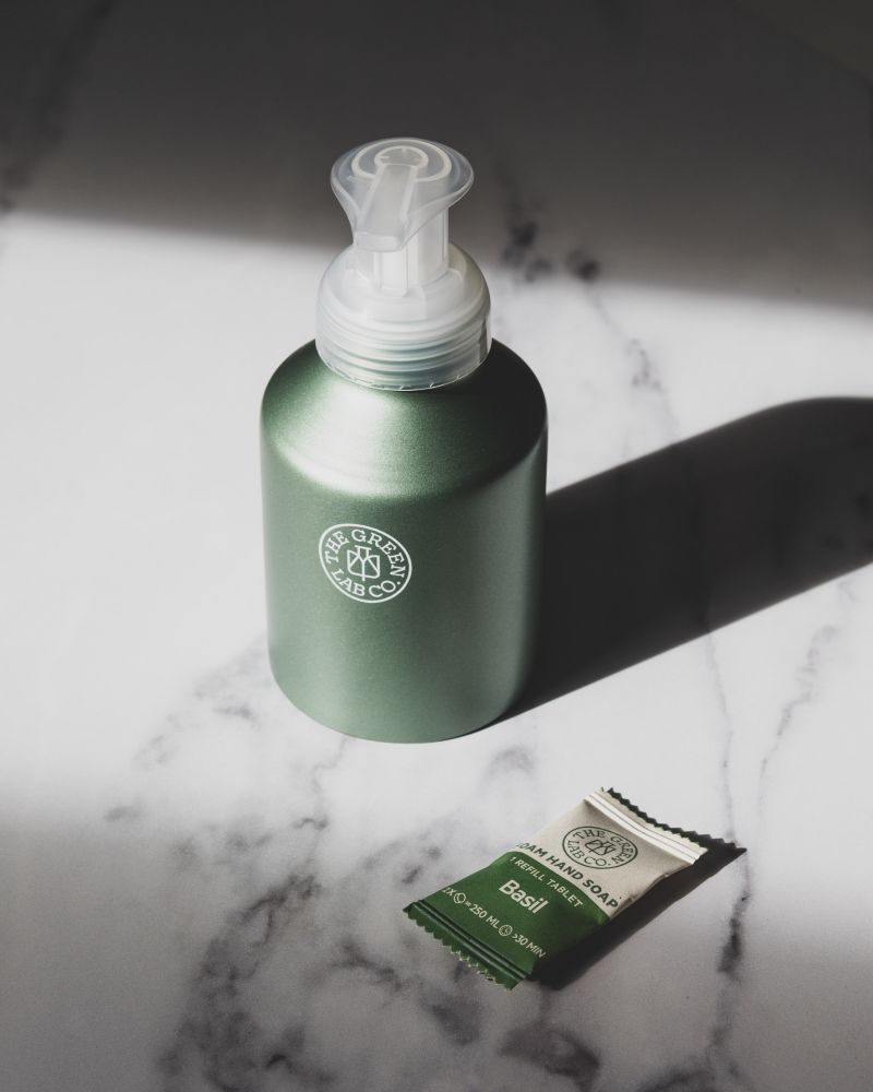 Groene pompflacon met natuurlijke shampoo of body wash op marmeren ondergrond, minimalistische productfotografie voor duurzame verzorgingsmerken.