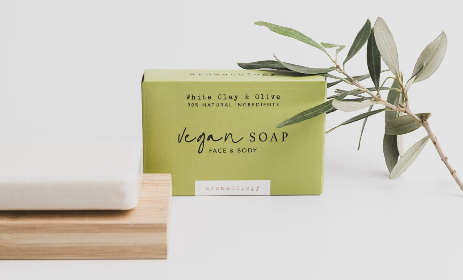Vegan zeep in kartonnen verpakking met olijftak en witte zeep gefotografeerd voor een duurzaam verzorgingsmerk